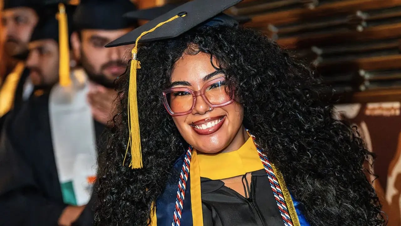Monroe University graduate wearing a red, white and blue military honor cord at commencement